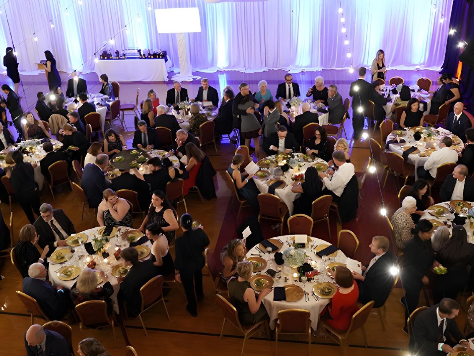 Elegant dinner event with people seated at round tables in a beautifully lit venue